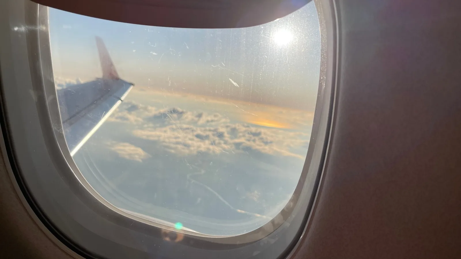 機内の窓から見た、翼と雲、夕方の空