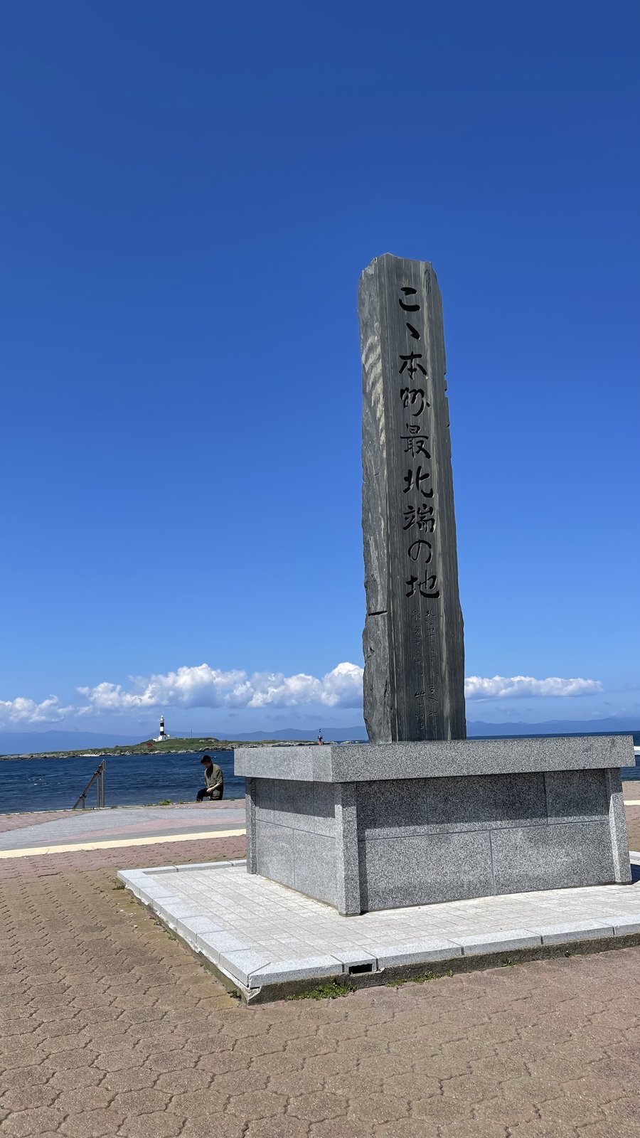 大間崎に立つ「こゝ本州最北端の地」の石碑と、その向こうに広がる海