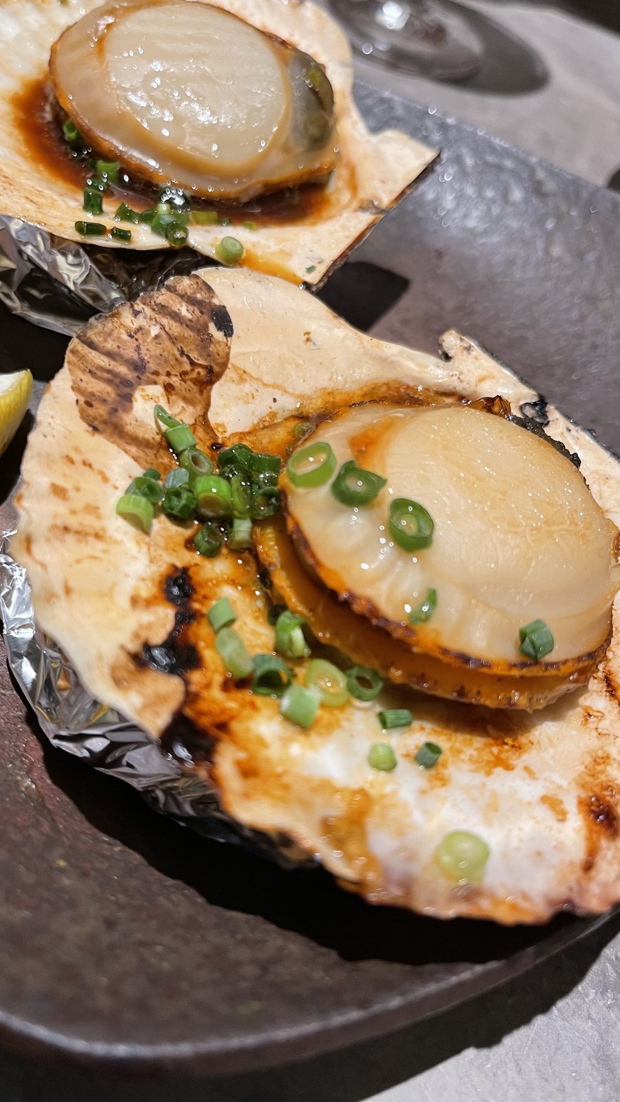 貝殻ごと焼かれた、ねぎをのせたホタテの貝焼き